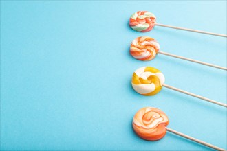 Four lollipop candies on blue pastel background. copy space, side view