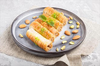 Baklava, traditional arabic sweets in gray ceramic plate on a gray concrete background. side view,