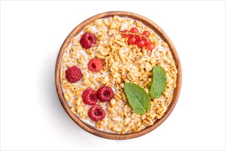 Wheat flakes porridge with milk, raspberry and currant in wooden bowl isolated on white background.