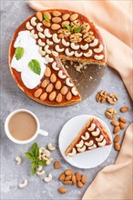 Homemade cake with caramel cream and nuts with cup of coffee on a gray concrete background. top
