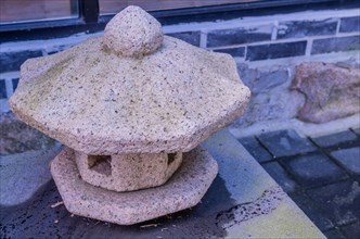Carved rock lantern on porch step with blurred background in South Korea