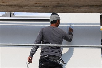 Painter and plasterer working on the facade of a new residential building (Mutterstadt development
