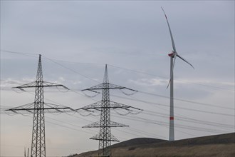 High-voltage pylons with wind turbine in German industrial landscape