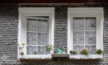 Slate-clad house facade, two windows and decoration made of artificial flowers, historic old town,