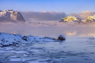 Eisige Landschaft mit Eisplatten im Fjord und einem idyllischen Dorf in den verschneiten