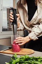 Unrecognizable woman making purple smoothie with banana and black currant