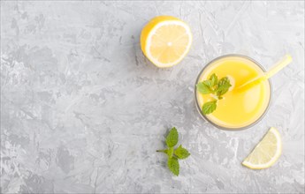 Glass of lemon drink on a gray concrete background. Morninig, spring, healthy drink concept. Top