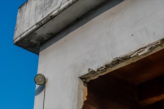 Flood light mounted on outside wall of abandoned concrete building with blue sky in background in