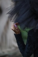 Close-up view of a woman's hand with tulle fabric against dark clothing