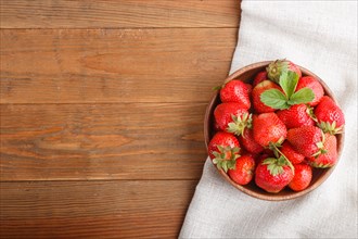 Fresh red strawberry in wooden bowl on wooden background. top view, flat lay, copy space