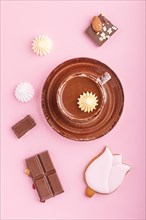 Cup of hot chocolate and pieces of milk chocolate with almonds on pink background. top view, flat