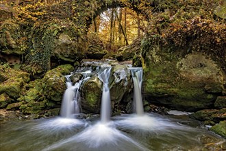 The three-armed Schiessentuempel waterfall in the Mullerthal in Luxembourg in sunny autumn weather