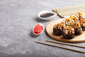 Japanese maki sushi rolls with cream cheese, chopsticks, soy sauce and marinated ginger on wooden