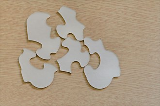 Assorted puzzle pieces laying upside down on brown wood grain tabletop