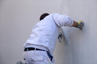 Plasterers plaster the facade of a new building (Mutterstadt development area,
