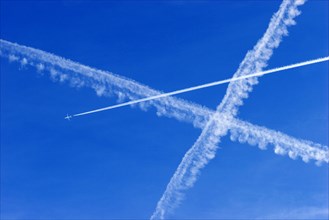 A passenger plane with vapour trails high in the blue sky