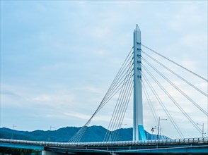 Modern suspension bridge against a cloudy blue sky, symbolizing engineering and transportation, in