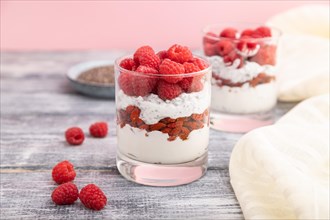 Yogurt with raspberry, goji berries and chia seeds in glass on gray wooden background and linen