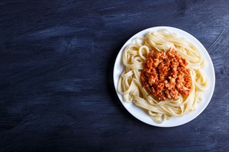 Fettuccine bolognese pasta with minced meat on black wooden background. top view, copy space