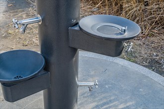 Black metal water drinking fountains near walkway in a public park in South Korea