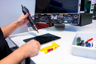 Side view of an unrecognizable technician fixing a computer component using a soldering iron in a