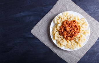 Farfalle bolognese pasta with minced meat on black wooden background. top view, copy space