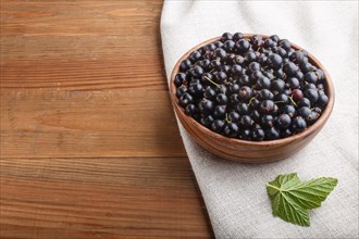 Fresh black currant in wooden bowl on wooden background. side view, close up, copy space