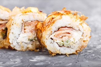 Japanese maki sushi rolls with tuna, cucumber, cheese on black concrete background. Side view,
