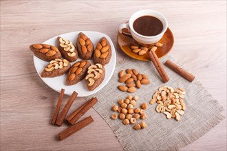 Small cakes potatoes with almonds and cashew nuts on a dessert plate. A cup of coffee, cinnamon,