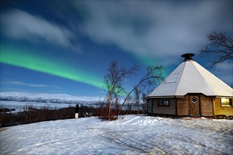 Northern Lights (aurora boreailis) over a small wooden hut in Swedish Lapland, Abisko, Kiruna,