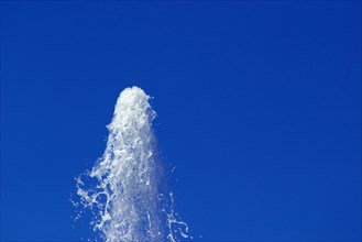 Water from a fountain in the blue sky