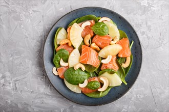 Fresh salmon with pineapple, spinach and cashew on a gray concrete background. Top view, close up,