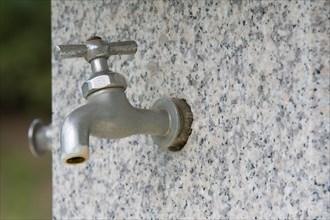 Closeup of water faucet on marble water fountain in public park in South Korea