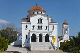 A whitewashed church with a red roof and a dome under a clear blue sky, Greek Orthodox Church of