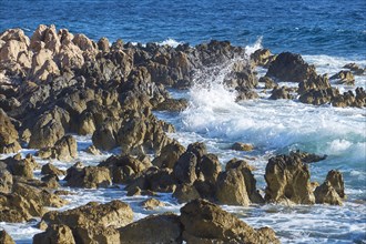 Wild sea meets a rocky coastline with splashing waves and spray, Methoni sea fortress, Peloponnese,