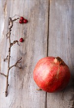 Ripe garnet with a branch on a rustic wooden background
