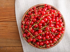 Fresh red currant in wooden bowl on wooden background. top view, flat lay, close up