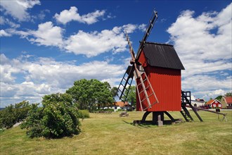 Red traditional windmill in a rural setting with a wide sky, meadow, Oeland, Sweden, Europe