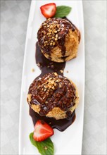 Fresh profiteroles with ice cream and chocolate on a white plate. selective focus. horizontal. top