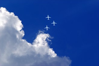 Three white passenger airplanes in blue sky