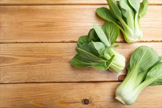 Fresh green bok choy or pac choi chinese cabbage on a brown wooden background. Top view, copy