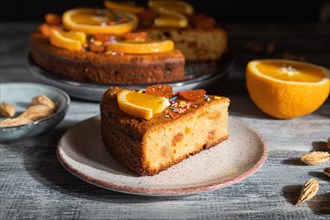 Orange cake on a gray wooden background. Hard light. contrast, low key. Side view, close up