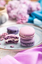 Purple macarons or macaroons cakes with cup of coffee on a white concrete background and
