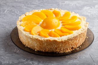 Round peach cheesecake on a gray concrete background. side view, close up