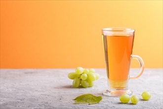 Glass of green grape juice on a gray and orange background. Morninig, spring, healthy drink concept