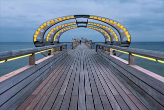 Long exposure of the Kellenhusen pier on the Baltic Sea with yellow illuminated arcades