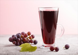 Glass of red grape juice on a gray and pink background. Morninig, spring, healthy drink concept.