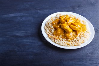 Rice with chicken curry sauce with cashew on black wooden background. close up, copy space