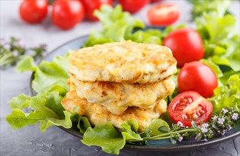 Minced chicken cutlets with lettuce, tomatoes and herbs on a gray concrete background. side view,
