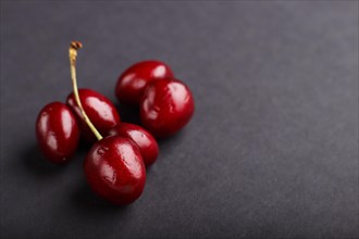 Ugly weird red sweet cherry on black background. side view, close up, copy space, macro, trendy